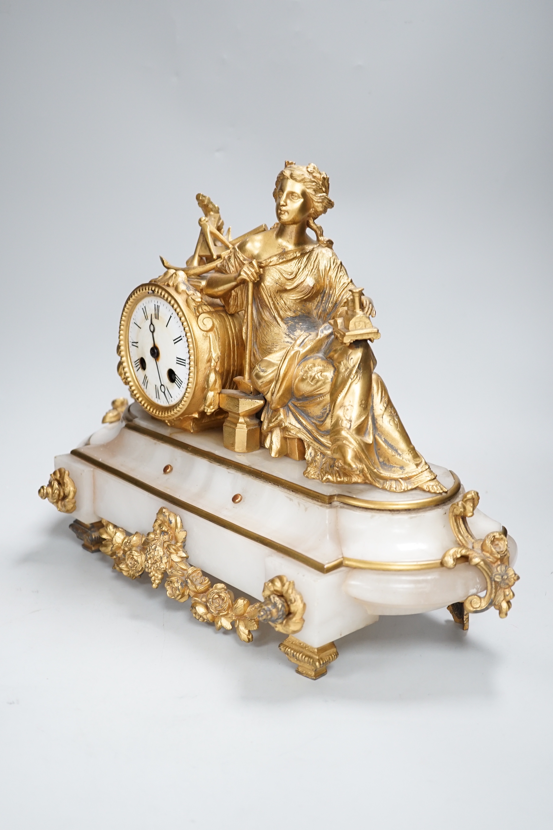 A late 19th century French gilt metal and onyx clock mounted with the figure of Industry holding a locomotive, 42cm wide